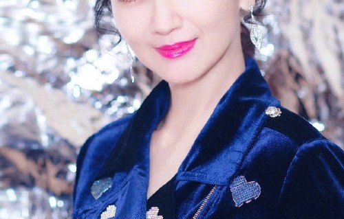 赵雅芝身着深蓝色丝绒套装，在一片银色金属质感的背景墙前摆pose|十分